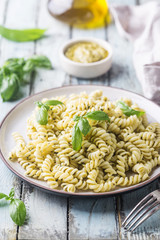 Italian fusilli pasta with fresh homemade pesto sauce on a plate over white wooden background