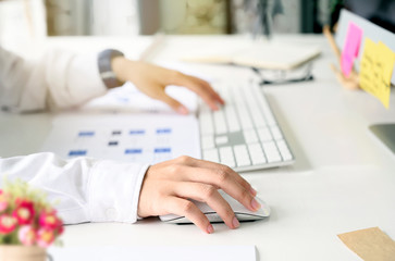 Cropped shot female hand using mouse working with computer at office.