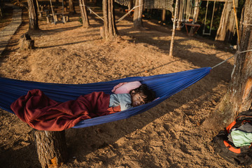 young asian kid relaxing on hammock outdoor in the wood