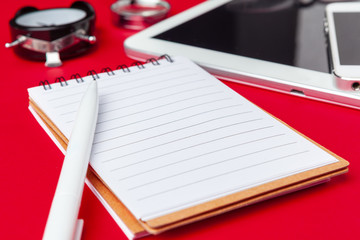 Red office desk table with blank notebook, keyboard and supplies. Top view with copy space. Flat...