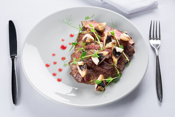 chopped beef steak with champignons, young peas and red sauce
