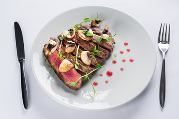 chopped beef steak with champignons, young peas and red sauce