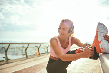 So happy Close up of cheerful disabled woman in headphones stretching prosthetic leg and listening...
