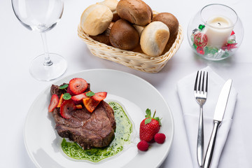 beef stake with strawberry on white dish and basil saus