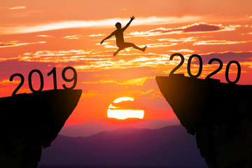 Businessman jumping between 2019 and 2020 years on sunrise background,Happy new year concept.