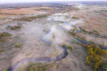 Autumn foggy river from above. Aerial view of river in morning fog