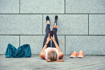 Relaxing after training. Top view of woman with leg prosthesis in sports clothing holding her...