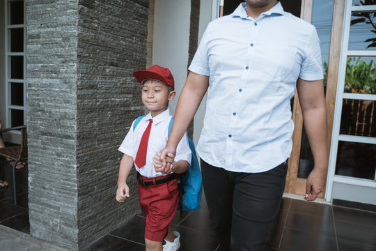 asian boy hold his father's hand and going to school in the morning