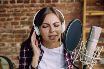 Woman in headphones recording music video blog home lesson, singing or making broadcast internet...