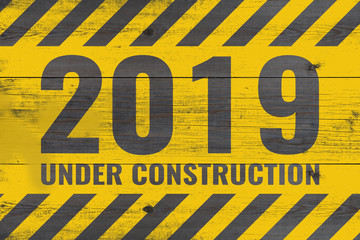 2019 under construction warning message painted on aged wooden planks