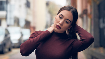 Sad young woman posing on the street.