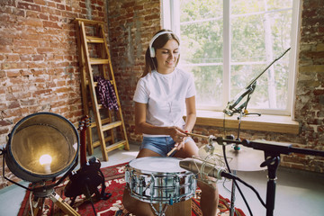 Woman in headphones recording music video blog home lesson, playing drums or making broadcast...