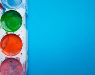 multicolored paint and brush on blue background