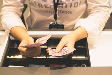 Employees are counting money in the shop for customers to buy. Woman's hand