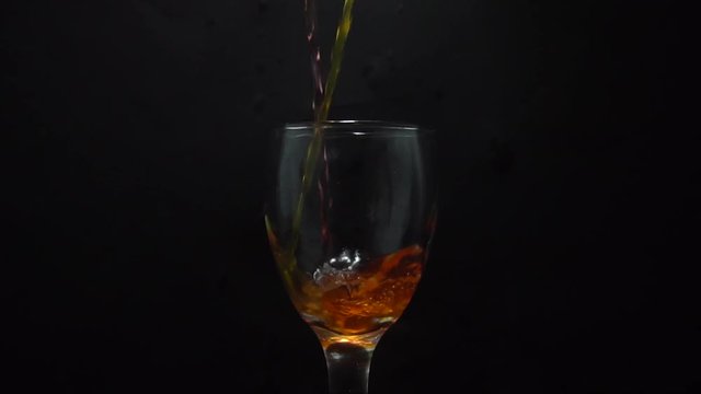 Pouring Fresh Orange juice in wmpty glass isolated on black background
