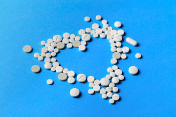 Heart shape made from white pills on blue background - Image