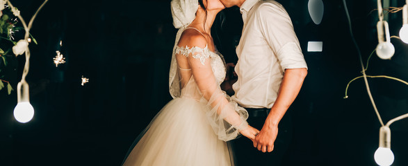 Beautiful couple is hugging near white flowers arch at the wedding ceremony. Outdoors decoration....