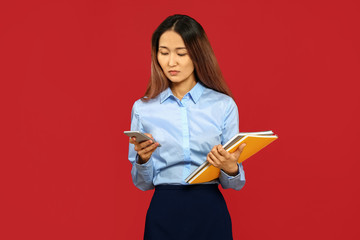 Asian businesswoman with mobile phone on color background