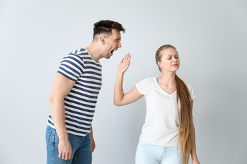 Young quarrelling couple on light background