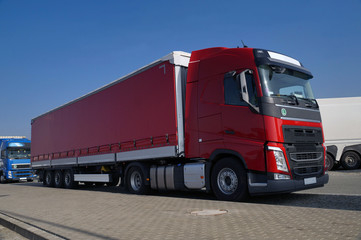 Various types of trucks in the parking lot next to the motorway.
