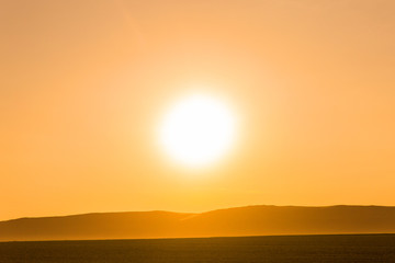 Beautiful sunrise in the desert. Bright sunlight. Silhouette of mountains