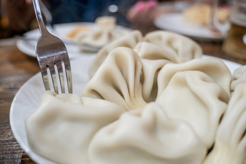 Georgian traditional cuisine food Khinkali on a plate with a fork, top view close up