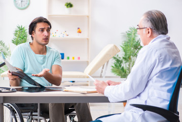 Male patient in wheel-chair visiting old doctor