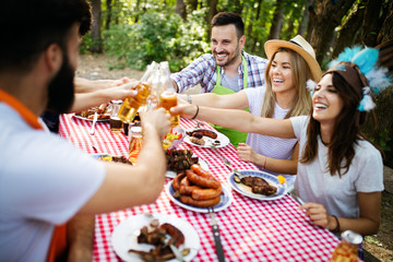 Happy friends camping and having a barbecue in nature