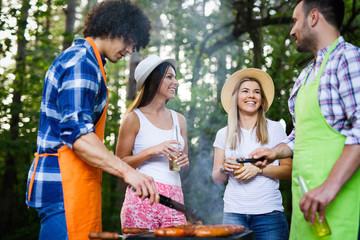 Obraz premium Group of happy friends having a barbecue party in nature