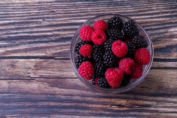 Raspberries and blackberries on a wooden table