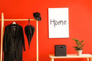 Stylish umbrella with coat hanging on clothes rack in hall