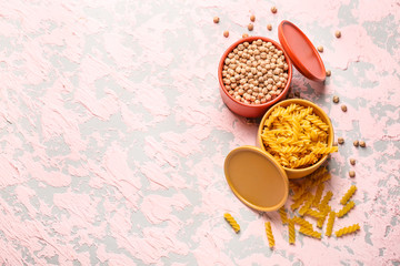 Containers with raw products on color background