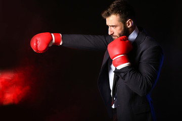 Businessman in boxing gloves on dark background