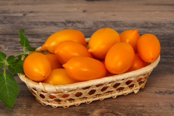 Yellow tomato heap in the wooden bowl