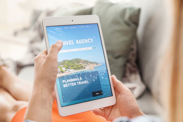 Woman with tablet computer visiting travel agency website at home