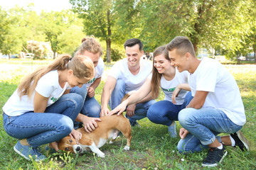 Group of volunteers with cute dog outdoors