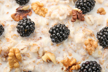 Tasty sweet oatmeal with blackberry and nut, closeup