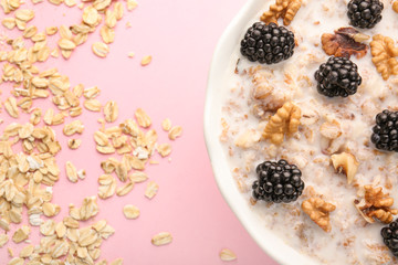 Bowl with tasty sweet oatmeal on color background