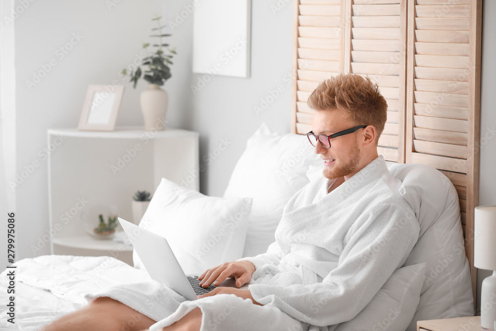 Poster Morning of young man with laptop in bedroom