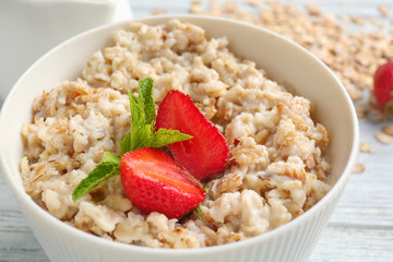 Bowl with tasty sweet oatmeal on table, closeup