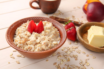 Bowl with tasty sweet oatmeal on wooden table