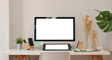 Blank screen computer and tablet in modern office room