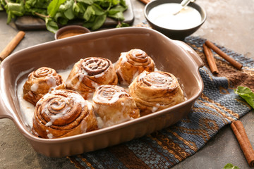 Baking tray with tasty cinnamon buns on table