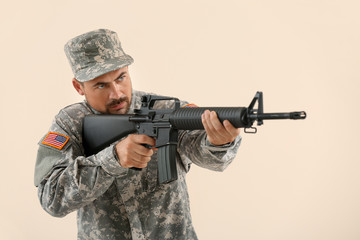 Soldier in camouflage taking aim on light background