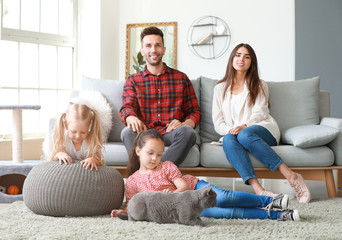 Happy family with cute cat resting at home