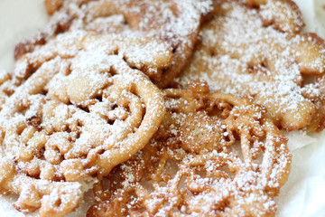Homemade funnel cakes with powdered sugar on a ceramic plate.