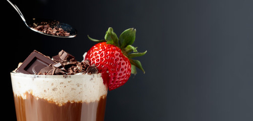 Chocolate drink with whipped cream, strawberry and pieces of black chocolate.