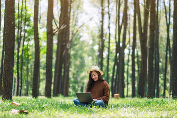 Obraz premium A woman working and typing on laptop keyboard while sitting in the park