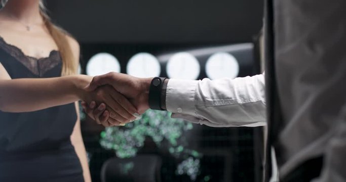Business meeting, woman with glasses shaking hands with a african businessman colleague, a handshake in the office.