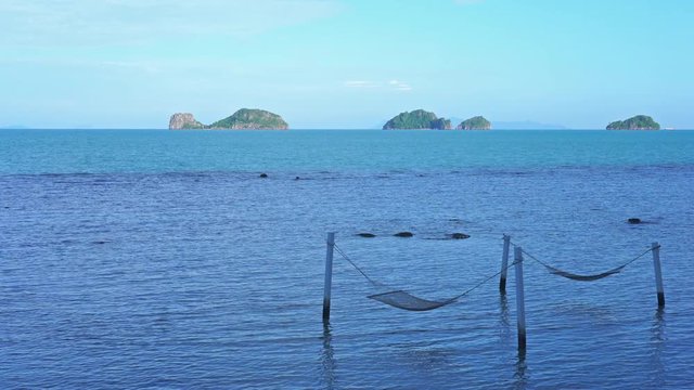 Perfectly positioned hammocks between white pols in the shallows with a view of raggedy islands out in the ocean